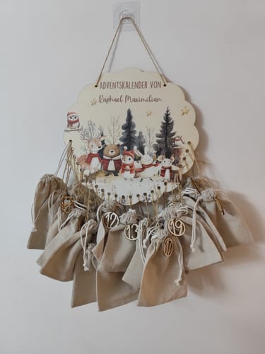 Kunde zeigt den personalisierten Holz-Adventskalender mit Jutesäckchen und Zahlen, der an einer Wand hängt.