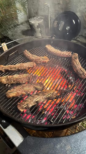Cliente asando unas ricas y jugosas costillas en la parrilla.