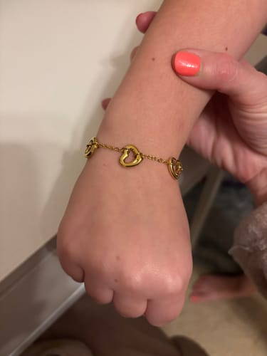 Customer's close-up of a gold-colored heart charm bracelet from the Advent Calendar on a wrist.