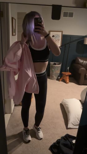 Customer in a mirror selfie wearing The Square Bra in black with white binding and matching leggings.