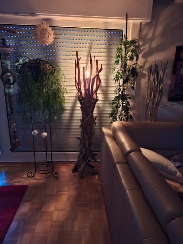 Kundenfoto der eingeschalteten Treibholz Stehlampe VILLA in einem modernen Wohnzimmer vor einem Fenster.