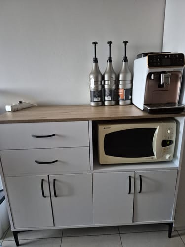 Müşterinin kahve köşesi olarak kullandığı beyaz ve ceviz renkli çok amaçlı dolap, üzerinde bir kahve makinesi ve içinde bir mikrodalga.