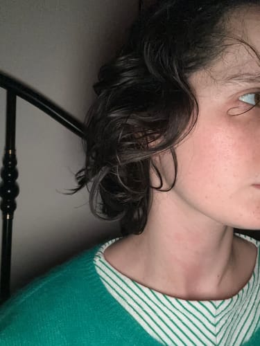 Vue de côté des cheveux courts et foncés d'une cliente prenant une cure pour la pousse des cheveux.