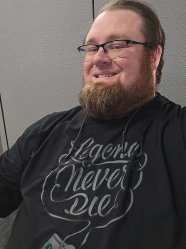 Reviewer smiling while wearing the black Legends Never Die performance hoodie, showing the front script graphic.
