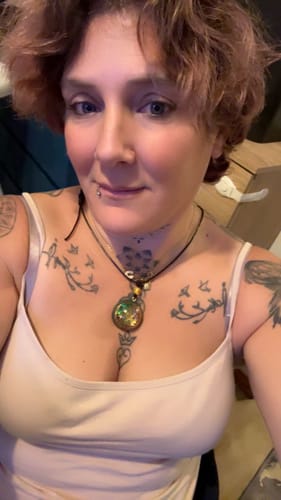 Cliente montrant son Talisman Énergétique Sacré, un pendentif irisé, autour du cou.