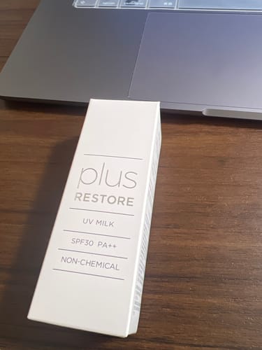 レビュアーによる、机の上のノートパソコンの前に置かれたUVミルクの白いパッケージ。