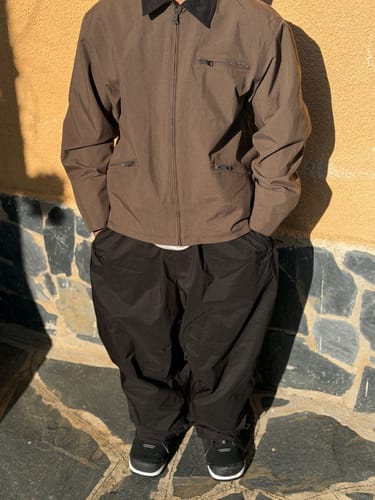 Customer wearing the baggy black snow pants with a brown jacket, standing outdoors.