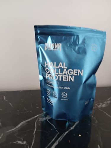 Customer's blue pouch of Halal Collagen Protein resting on a black marble countertop.