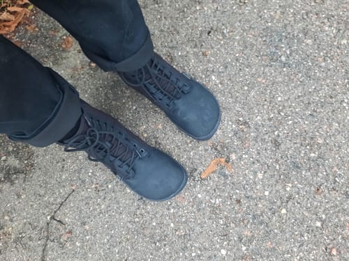 Arvostelijan mustat Vaistoa Hurmos -paljasjalkamaiharit jalassa, kuvattuna ylhäältä päin asfaltilla.