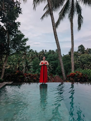 Reviewer's photo using BALI LIGHTROOM PRESETS, showing a person in a red dress at an infinity pool overlooking a jungle.