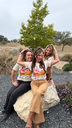 Three reviewers playfully posing together outdoors in their matching 'Sure I'll Just Cook For All You' tees.