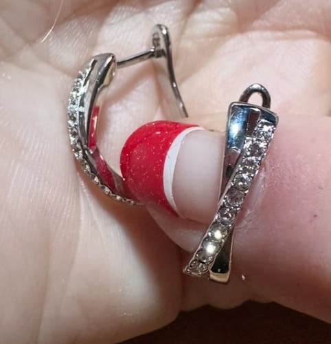 Close-up of a reviewer holding one sparkling Amaya twisted hoop earring to show the crystal details.