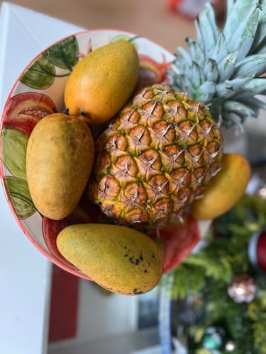 Kundenbewertung: Mehrere ganze „Ataulfo“-Mangos in einer bunten Obstschale neben einer Ananas.