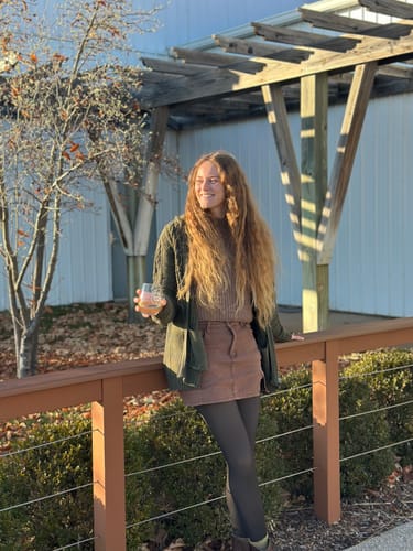 Reviewer standing outdoors wearing the dark, sheer illusion fleece-lined tights with a skirt.