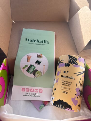 Un cliente muestra el envase del Té Matcha Vainilla Premium dentro de la caja de envío junto a un folleto.