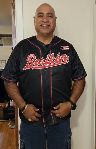 Reviewer smiling while wearing the black Puerto Rico Heritage Custom Baseball Jersey with 'Borikén' across the chest.
