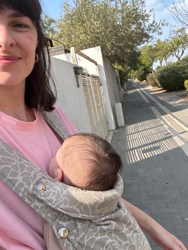 Reviewer takes a selfie while their baby sleeps in the patterned Urban Minimal - forest carrier.