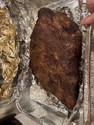 Customer's cooked USDA Prime Brisket with a dark crust, resting in a foil-lined pan.