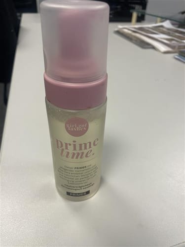 Die Kundin zeigt ihr Gratis-Geschenk: eine große Flasche des „girl got lashes“ Primers auf einem Tisch.