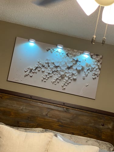 Customer's White Cherry Blossom Wall Art hanging in a bedroom above a headboard, illuminated by cool-toned lights.