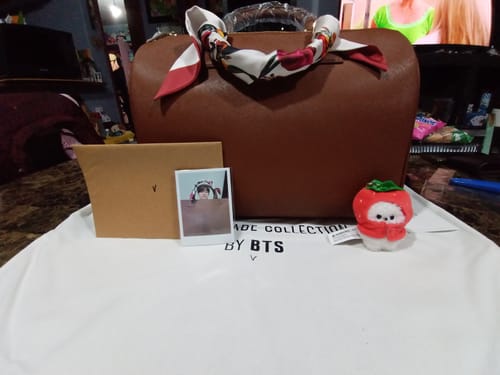 Reviewer's brown Mute Boston bag from the Artist-Made Collection by BTS V, shown with its dust bag and other included items.