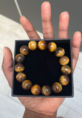 Client présentant le bracelet Oeil de Tigre avec de grosses perles lumineuses dans sa boîte.