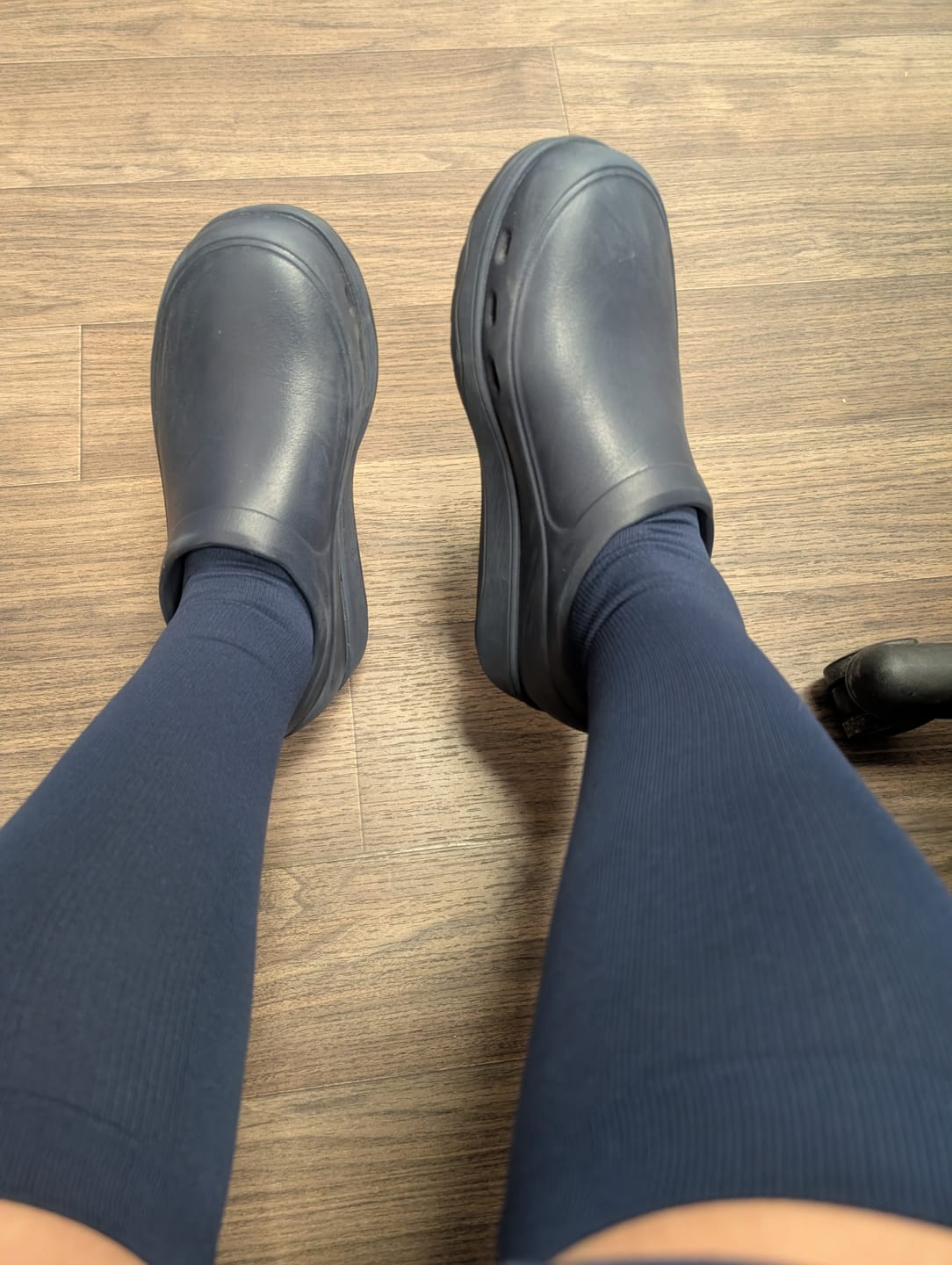 Customer's point-of-view wearing the blue Everstride™ Compression Socks with dark blue clogs.