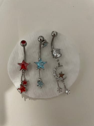 Reviewer's Twinkle of the Moon Belly Dangle displayed with two other star-themed belly rings on a cotton pad.