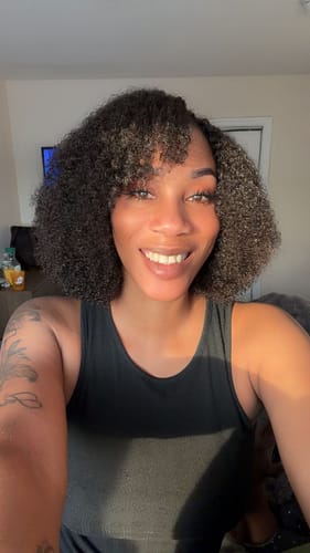 Reviewer showing off her soft Multi-Textured Kinky Curly Crochet Hair styled in a shoulder-length bob with bangs.