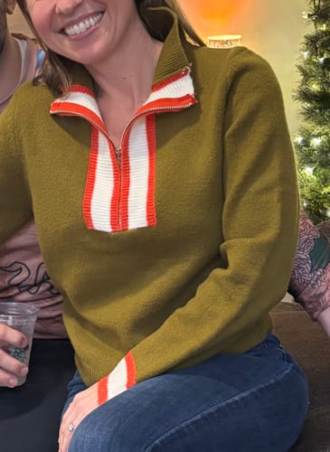 Reviewer wearing the Sasha Quarter Zip Sweater in olive green with the collar popped, showing red and white striped details.