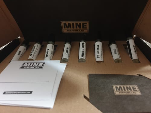 Il recensore mostra il set di campioni orientali e legnosi nella sua scatola aperta, con le 8 fiale di profumo allineate.