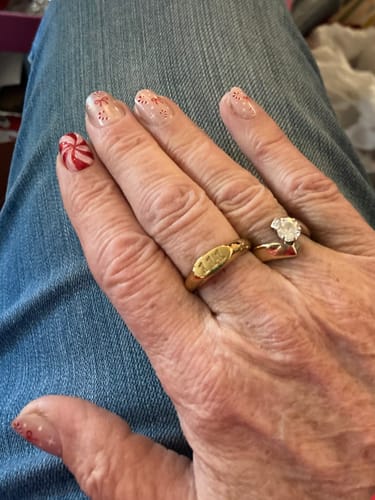 A customer's hand wearing the gold Angelica Angel Number Signet Ring on the middle finger.