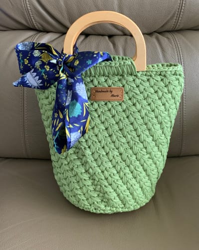 Reviewer's finished light green Crochet Bag with wooden handles and a blue patterned scarf tied to the side.