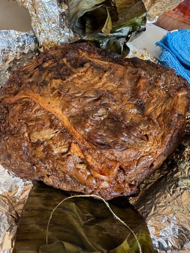 Reseñador muestra la Rib Eye Pieza Básica horneada entera sobre papel de aluminio y hojas de plátano.