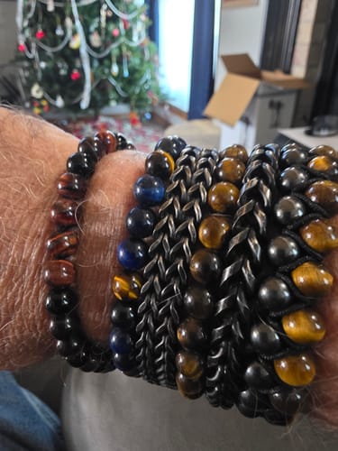Customer wearing the R.E.D. Tiger's Eye Never Forget Bracelet on their wrist, stacked with several other bracelets.