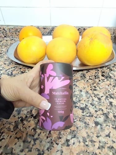 Cliente sosteniendo el bote de Té Matcha Premium Cacao en la encimera de una cocina.