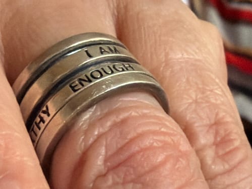 Close-up of a reviewer's hand wearing the sterling silver Fidget Ring with the affirmations 'I AM' and 'ENOUGH' visible.