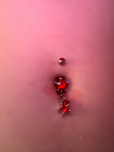 Close-up: Customer wearing the Seeing Stars Belly Dangle with festive red star-shaped gems.