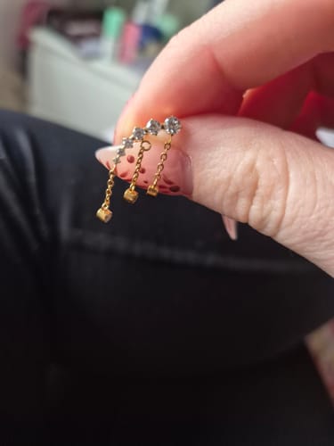 Customer holding the Drippy Chained Flatback Gold earring, showing the detailed gems and dangling chains.