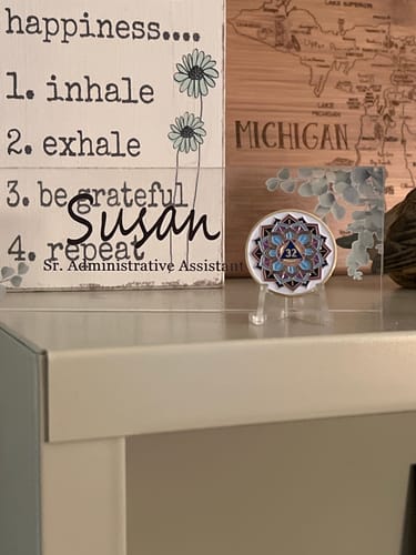 Reviewer's 'In Bloom' Lotus Flower sobriety medallion displayed on a stand on an office shelf.