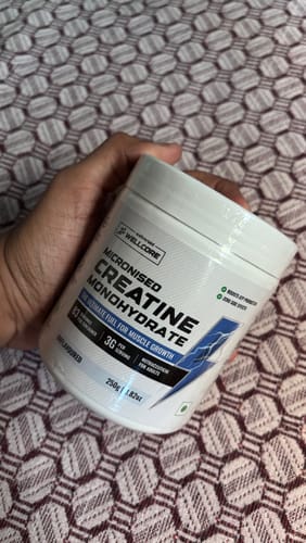 Customer's hand holding a white tub of Wellcore Micronised Creatine Monohydrate.