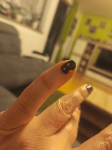 Nahaufnahme der Hand einer Rezensentin, die die dunklen 'Decking The Halls'-Nagelfolien nach über einer Woche Tragezeit zeigt.