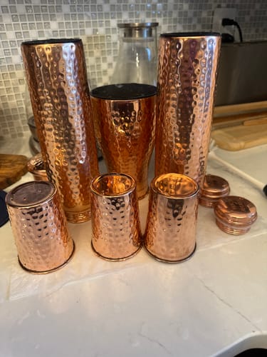 Customer's collection of hammered copper Himalayan Ayurvedic Bedside Carafes and cups on a counter.