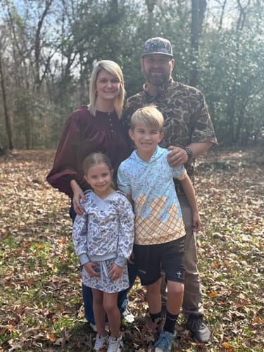 Customer's son wearing the black 'Minimal Cross' Youth Performance Shorts in an outdoor family photo.