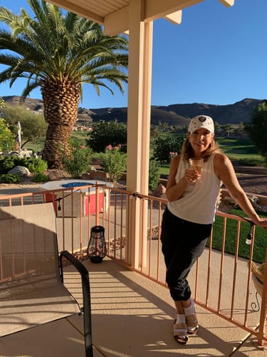 Reviewer holding a glass of Lamborghini Rosè wine on a sunny patio.