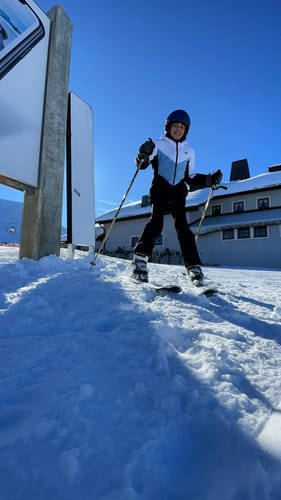 Reviewer wearing Gsou Snow gloves while skiing in the snow on a sunny day.