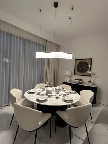 Reviewer's Stardust Swirl Pendant Lamp illuminated over a modern, round dining table.