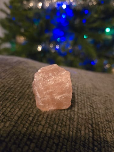 Customer's uncut rose quartz crystal from the VIP Crystal Club resting on a dark, textured surface.