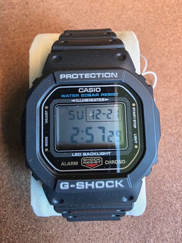 Reseñador muestra un primer plano del resistente reloj Casio G-Shock DW-5600UE-1JF negro.