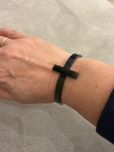 Reviewer's wrist wearing the black Conquer Death cuff bracelet, which features a cross design.